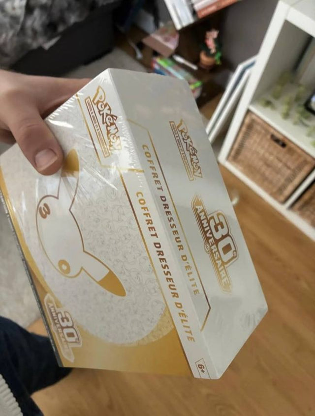 Coffret Dresseur d'Élite 30e anniversaire scellé, tenu en main par un client